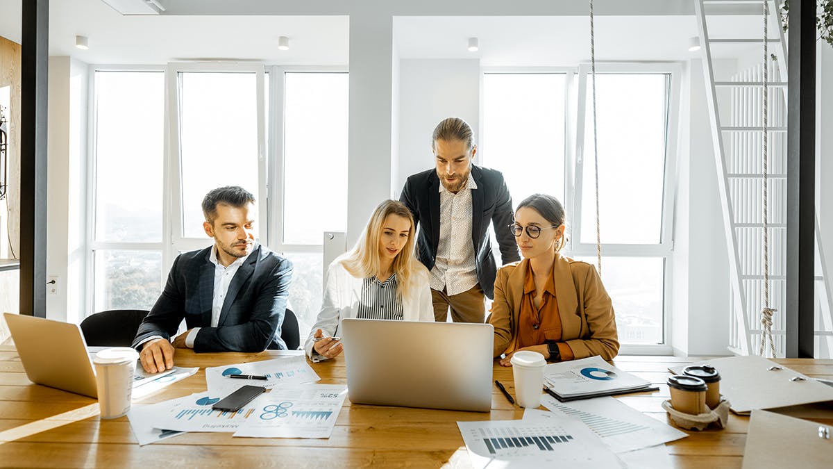 Four corporate looking business people meeting in an open coworking space